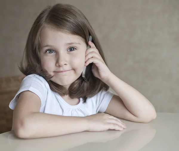 人々、子供と技術コンセプト - スマート フォンを持つ少女。言えば、聖体拝領。テーブルに座って彼女の電話で話す美しい赤ちゃん — ストック写真