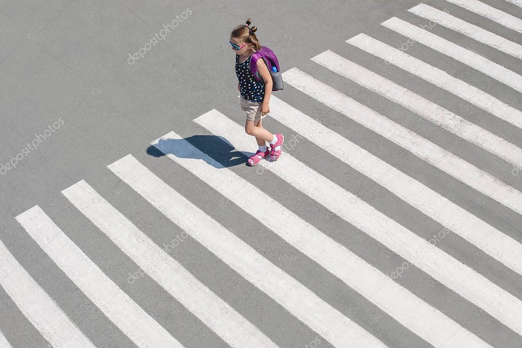 Schoolgirl crossing road on way to school. Zebra traffic