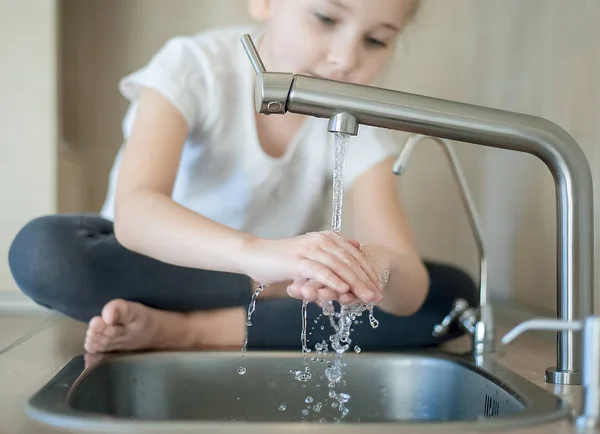 Close up of little girl washing hands In kitchen sink at home — Stock Photo, Image