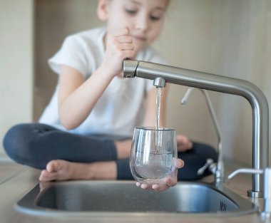 Kid pouring fresh water from filter tap