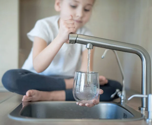 Niño vertiendo agua dulce del grifo del filtro — Foto de Stock