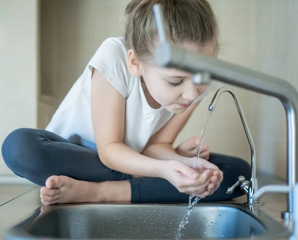 Niña caucásica bebiendo del grifo o grifo de agua —  Fotos de Stock