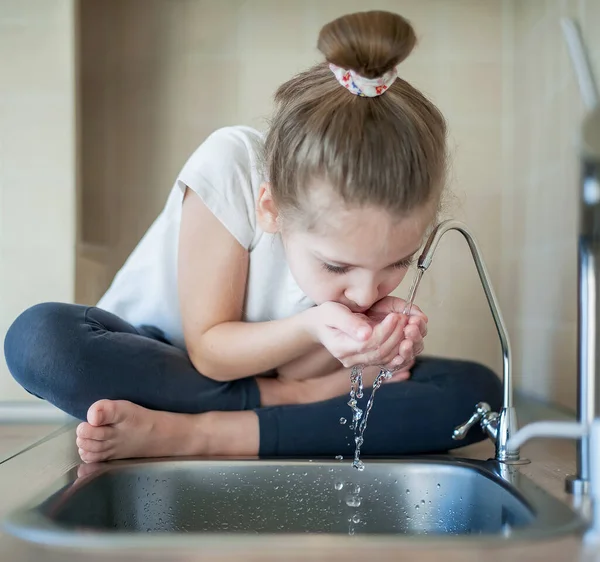 Niña caucásica bebiendo del grifo o grifo de agua —  Fotos de Stock