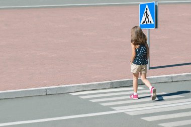 Moda elbiseli şık çocuk yaz kenti yaya geçidinde yürüyor. Yaya kaldırımında yürüyen bir çocuk. Yaya geçidinden geçen yayalar. Trafik kuralları böyle. Yukarıdan bakınca. Zebra geçidindeki gölge