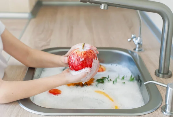 Apple in soapy foam. Disinfection measures: cleaning, washing fruits with antiseptics, water and soap in a kitchen sink. Corona virus prevention. Hygiene to stop coronavirus. Healthcare concept
