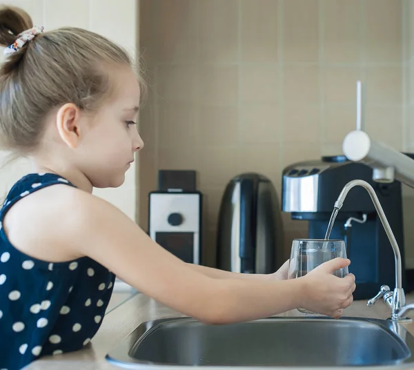 Evdeki mutfakta taze ters osmoz döken çocuk arıtılmış su. Musluk suyu içmek. Musluk suyu tüketimi plastik şişelerde su tasarrufuna katkıda bulunur. Çevreyi koruma