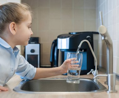 Evdeki mutfakta taze ters osmoz döken çocuk arıtılmış su. Musluk suyu içmek. Musluk suyu tüketimi plastik şişelerde su tasarrufuna katkıda bulunur. Çevreyi koruma