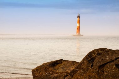 Okyanusu günbatımı zamanı yakınındaki iskele kayalar ötesinde ışık evi