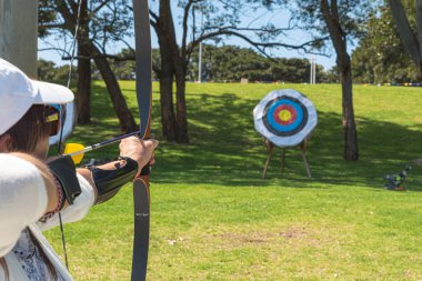 Parktaki okçuluk hedefine nişan alan spor kadını.