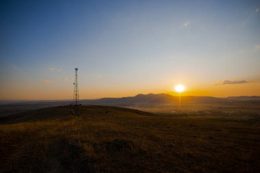 Yüksek voltaj kulesiyle sonbahar sahasında gün batımı
