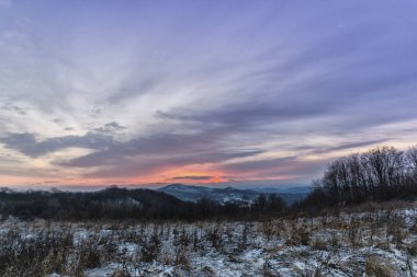 Gün batımında renkli gökyüzü ile karlı kış dağları