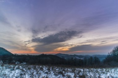 Gün batımında renkli gökyüzü ile karlı kış dağları