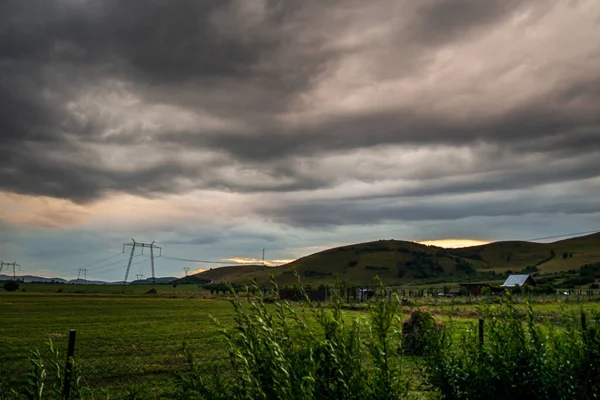 dark rainy sky over countryside landscape with electric power towers
