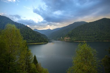 Dağlardaki görkemli göl, bulutlu günbatımı gökyüzü