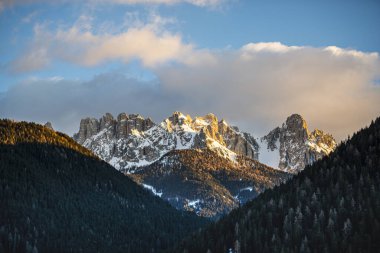 Gün batımı gökyüzü ve karla kaplı kayalık dağlar