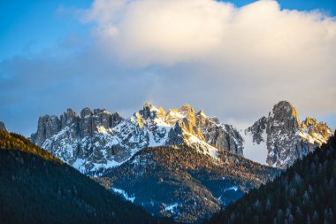 Gün batımı gökyüzü ve karla kaplı kayalık dağlar