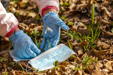 covid 19 kavramı, çayırdaki çiçekteki mavi eldivenler ve tıbbi maske.