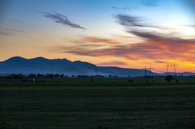 Kırsal alan ve günbatımı gökyüzü ve iletim elektrik hatları