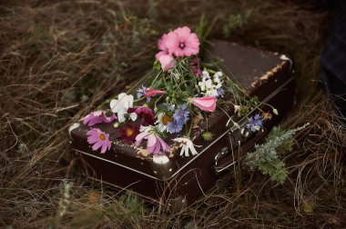 Bavul alan güzel çiçeklerle çim üzerinde yalan.