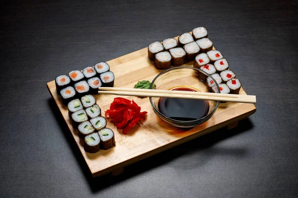 美味而又热又冷的寿司滚在桌上 不同的寿司卷和酱汁在日本菜盘上 — 图库照片