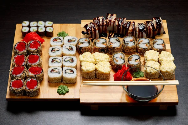 美味而又热又冷的寿司滚在桌上 不同的寿司卷和酱汁在日本菜盘上 图库图片