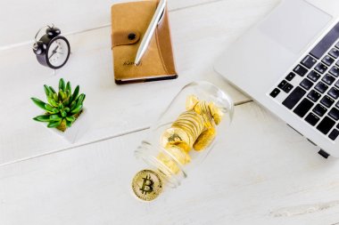 Ahşap masa, beyaz arka plan üzerinde Bitcoin sikke altın sikke izole cryptocurrencies bitcoin yığını üzerinde cam kavanoza Bitcoin sikke altın sikke. Cryptocurrencies en önemli cryptocurrency kavram olarak altın bir bitcoin ile kümesi.