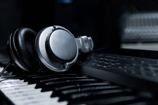 Müzik kulaklığı olan piyano klavyesi, piyano klavyesinde kulaklık, kapatma kulaklığı müzik aletleri arka planında elektrikli piyano arka planında..