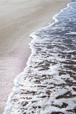 Kumlu sahilde yumuşak bir mavi okyanus dalgası. Arkaplan.