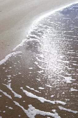 Kumlu sahilde yumuşak bir mavi okyanus dalgası. Arkaplan.