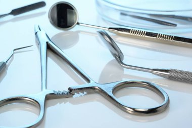 Diş aletleri: diş aynaları, spatula, kornzange ya da forseps, Petri kabında diş yanıkları. Mavi parlak yüzeyde diş aletleri, yakın plan.