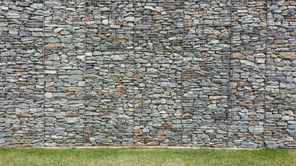 Malha parede de pedra e grama na frente — Fotografia de Stock