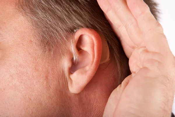 一个人的耳朵密切联系助听器. — 图库照片