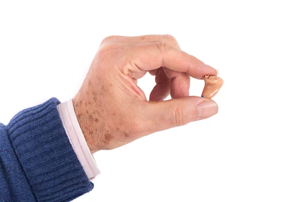 Mão de homem sênior mostrando um pequeno aparelho auditivo — Fotografia de Stock