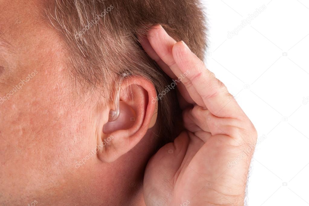Man wearing hearing aid cupping his hand behind his ear