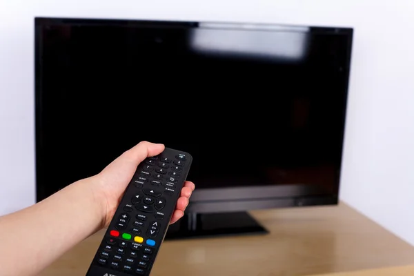 Hand using a remote control to turn off on the TV with an emp — стоковое фото