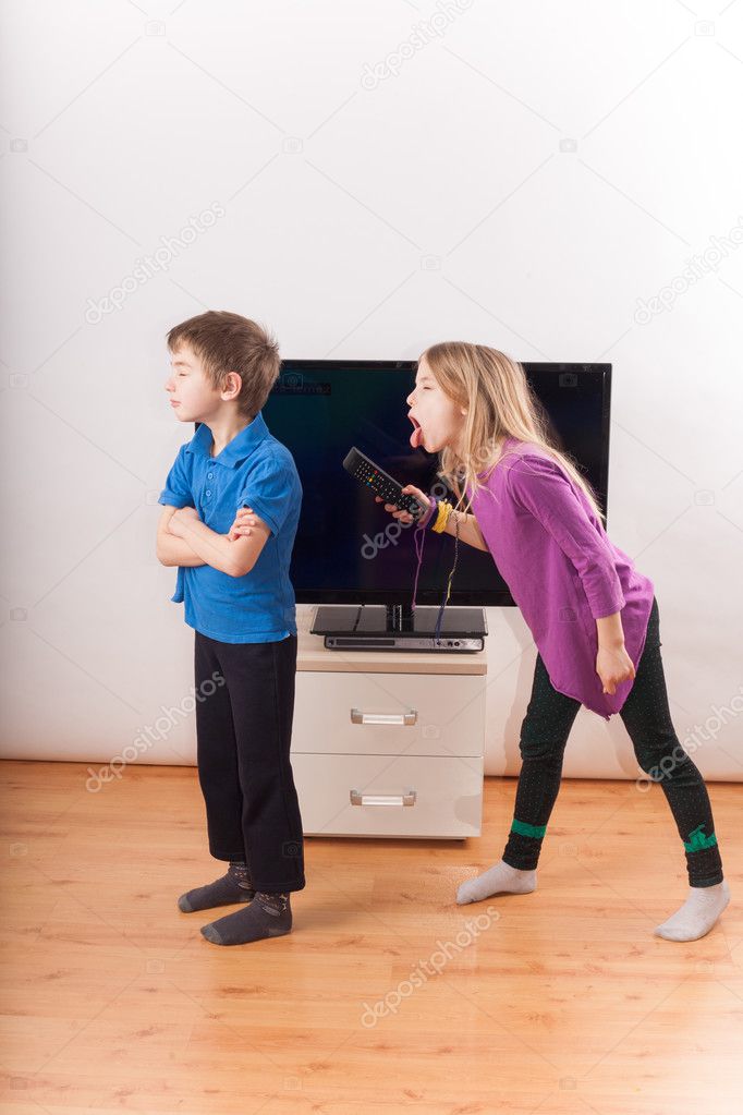 Siblings conflict over the remote control in front of the TV