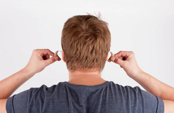 Vista posterior de la cabeza y las manos de un hombre sordo insertando su oído un — Foto de Stock