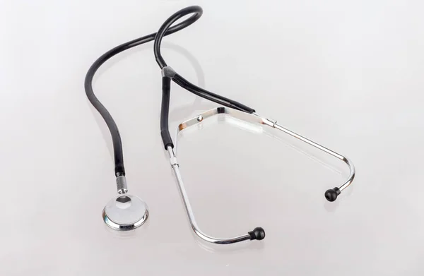 Stetoscopio medico isolato su superficie di vetro opaco riflettente — Foto Stock