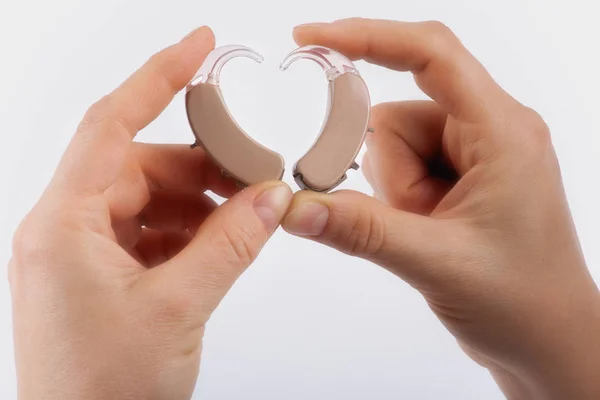 Руки, формирующие форму сердца из слуховых аппаратов — стоковое фото