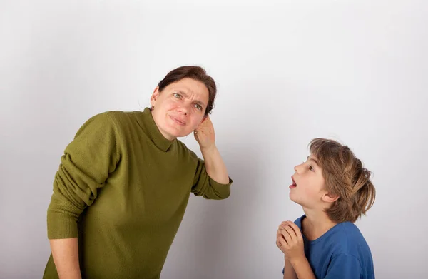 Madre acariciando su mano detrás de la oreja no puede oír a su hijo —  Fotos de Stock