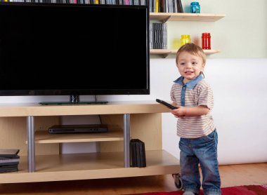 Uzaktan kumanda ile Tv karşısında mutlu yürümeye başlayan çocuk