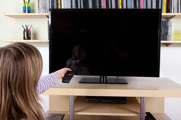 Νεαρή κοπέλα που κρατά απομακρυσμένου ελέγχου μπροστά από την τηλεόραση — Φωτογραφία Αρχείου