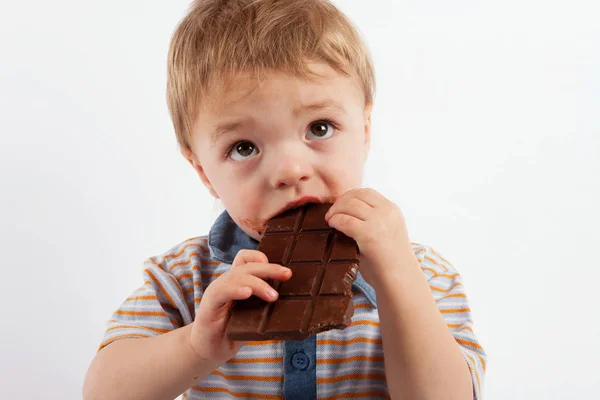 Sweet baby boy eating a chocolate bar — Stock Photo, Image