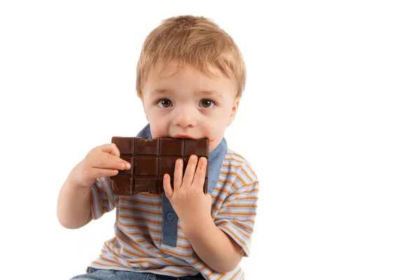 Lindo niño comiendo su gran barra de chocolate — Foto de Stock