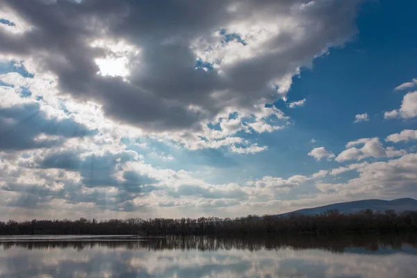 Paisaje tranquilo de un río con bonitos paisajes nublados y rayos de sol — Foto de Stock