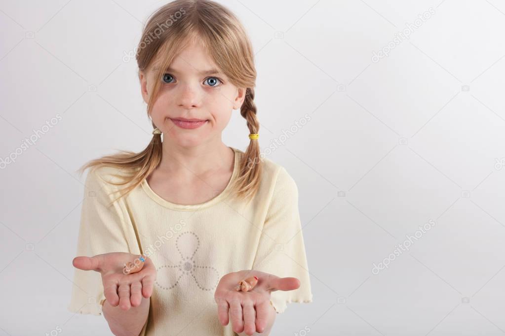 Adorable young girl showing hearing aids