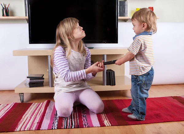 Girl arguing with her toddler brother over the remote control in