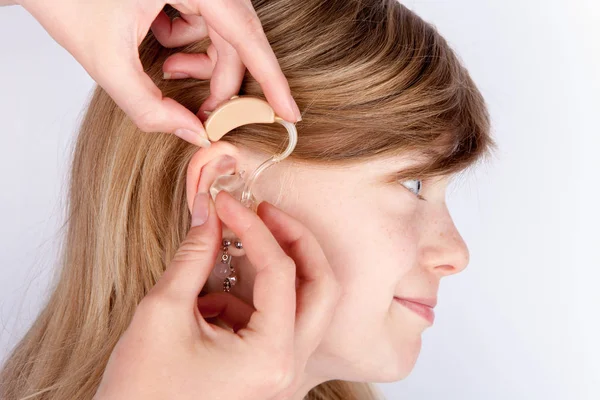 Doktor montáž mladá dívka s naslouchátko — Stock fotografie