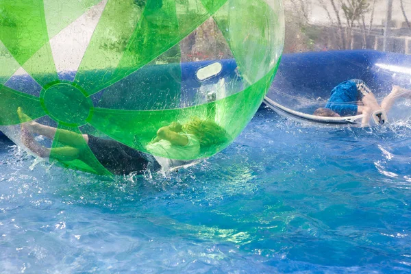 Дети играют на надувном пластиковом шаре на воде — стоковое фото