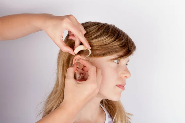 Close up of hands inserting a hearing aid in ear — Stock Photo, Image